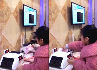 小女孩一边拆红包，一边把成叠钞票放进点钞机内。