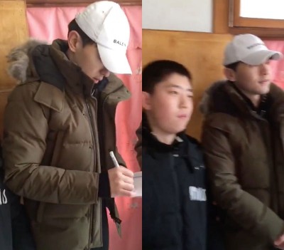 邓伦低头在本子上签名，接着马上和小弟弟合照。