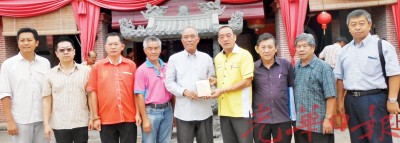 (右4起)沙巴州圣王宫及大伯公圣诞游行联合总会主席杨文吉赠送纪念刊物给宝福社副主席陈来福。