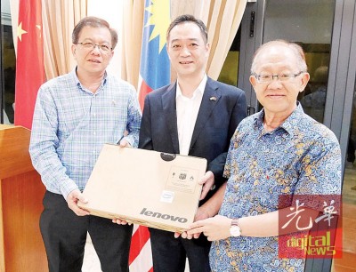 吴骏赠送纪念品手提电脑予本报,由骆南辉(左)及李兴前(右)接领。