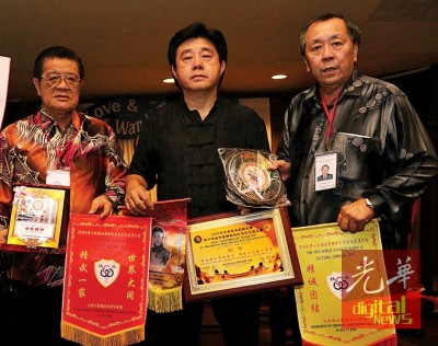 美国精武体育会总会总会长王国强(中)赠送纪念品予大马精武总会及怡保精武。左1为黄保生,右1为温炳楠。