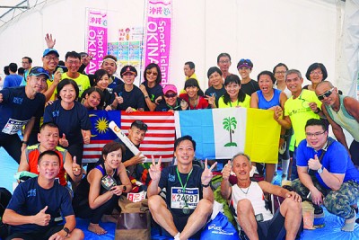 众团员跑完马拉松后，开心地拿着马来西亚国旗和槟州州旗合照。