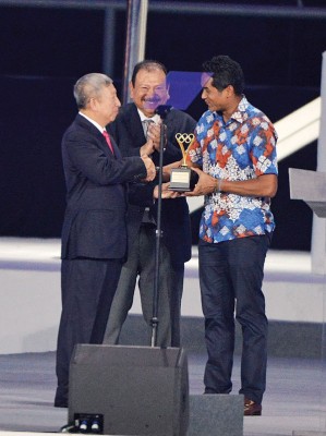 凯里（右起）在东姑英南的见证下，接受黄思绵代表国际奥理会颁发的褒奖。