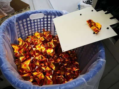 一个个折好的纸元宝滚入纸袋。