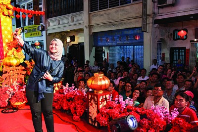 人美歌甜中国新歌声海选总决赛亚军艾徳玲（Wan Azlyn）献唱后，不忘在台上拿起手机与民众自拍。