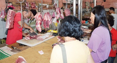 顾客在档口等待刘立贵（左）把猪肉切好。 