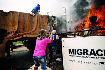 被拦截在委国边境的哥伦比亚物资货车突然起火，大批民众协助救火、转移救援物资。