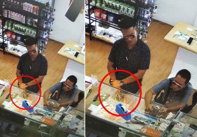 闭路电视画面清楚拍到两名涉案者戴着墨镜的样子，其中左边的已悄悄把包装好的手机（红圈处）拎在手中。