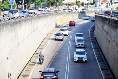 摩托车与轿车共用狭窄的车道。
